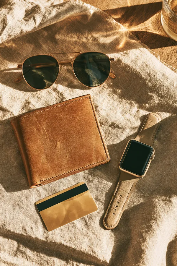 Flat lay of a slim leather wallet, sunglasses, a transit card and a smartwatch on linen, illustrating the Tripoint Lending personal loan vs credit card guide